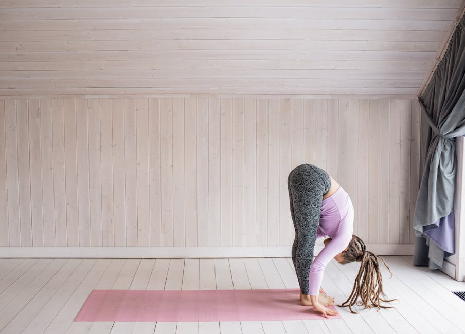 Person doing a seated forward bend yoga pose at home.